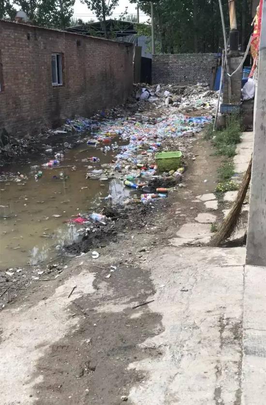 ▲涉事工厂大门处的露天垃圾堆,地面渗出发黄的污水,气味刺鼻。新京报记者 刘经宇 摄