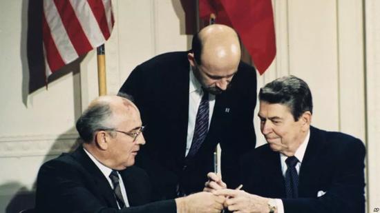 ▲资料图片：1987年12月8日，里根（右）与戈尔巴乔夫签署《中导条约》后交换签字笔。（美联社）