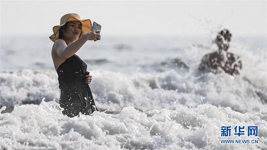游客在北海市银滩冲浪戏水（4月18日摄）。新华社记者张爱林摄