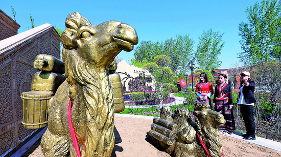 5月1日，北京世园会新疆室外展园里一组整装待发的丝路商旅驼队雕塑，吸引参观者驻足观看。