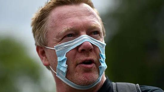  英国示威者将口罩剪破以示抗议。图源：《每日邮报》