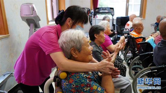 在位于北京市朝阳区的东方综合养老院，一位老人在护理员的指导下做手指操（8月7日摄）。新华社记者 孙少龙 摄