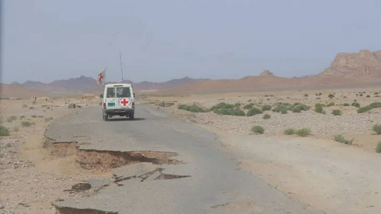 阿富汗境内，红十字会的救援车辆正驶过破碎的公路。图/红十字国际委员会
