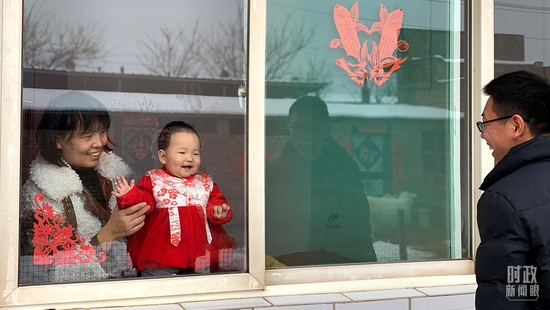 △蔡金隔窗逗女儿开心大笑。（总台央视记者段德文拍摄）