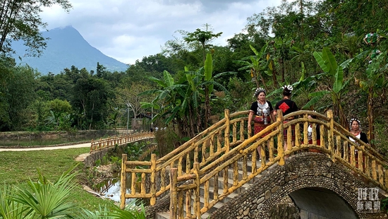  △五指山脚下的黎族村寨与当地村民。（总台央视记者段德文拍摄）