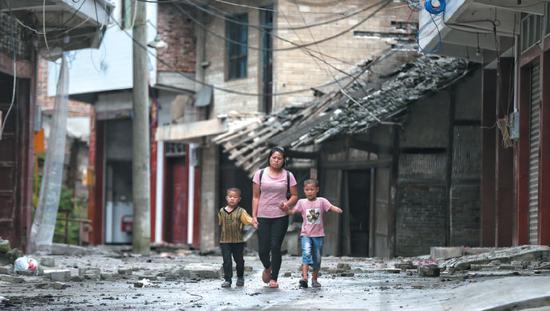  ▲昨日，四川省长宁县双河镇，一位母亲领着两个孩子准备去临时安置点休息。 新京报记者 彭子洋 摄 
