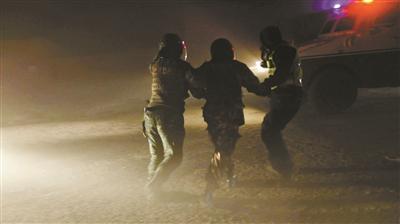 武警官兵帮被困者戴上头盔,在飞沙走石中将其引导至装甲车旁 供图/武警新疆总队克拉玛依支队