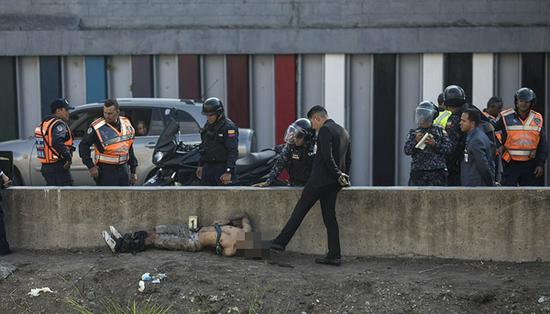 一名警察调查员用脚指着一名被绑住手脚的男子的头部