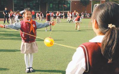 武汉市红领巾学校学生在操场上分组玩“穿梭拉拉球”游戏。本报记者 田豆豆摄
