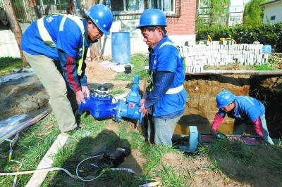 昨天，在昌平区华龙苑南里小区，施工人员正在安装电子远传水表。本报记者 饶强摄  