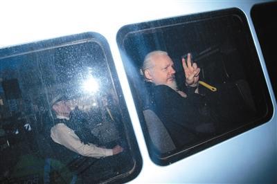 当地时间4月11日，伦敦，阿桑奇抵达法院，在警车里对媒体比手势。本版图片/视觉中国
