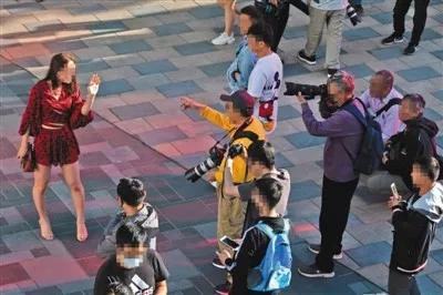 5月19日下午，三里屯太古里，一男性街拍爱好者指着经过的女性要求拍摄，该女性微笑拒绝并用手遮挡镜头。图源：新京报