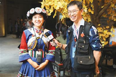 华文媒体代表（右）在体验用VR全景展现的纳西史诗《创世纪》后，对纳西族工作人员进行采访。杨浩明摄