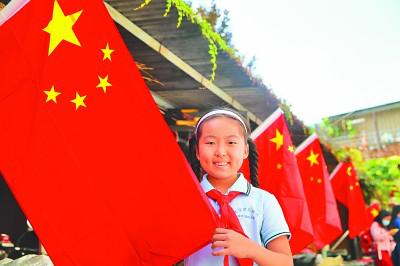 小学生与国旗合影，喜迎新中国成立71周年华诞。郭俊锋摄/光明图片