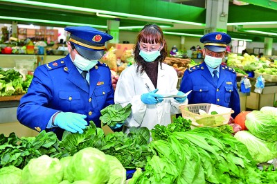 管理局工作人员与检测员在农贸市场对蔬菜取样,进行农药残留超标检测