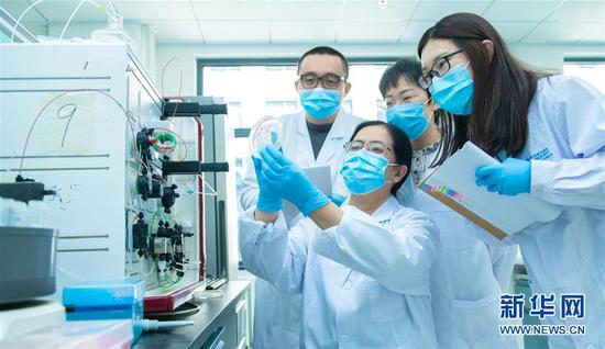3月20日，中国科学院微生物研究所研究员严景华与团队的学生们讨论实验结果。新华社发（王强 摄）