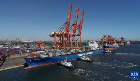 一艘轮船在拖轮的协助下向唐山港京唐港区集装箱码头靠泊（2021年10月23日摄，无人机照片）。新华社记者 朱旭东 摄