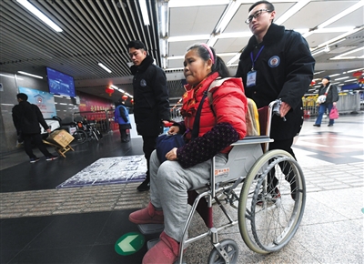 胡少杰（右一）用轮椅将腿脚不便的老人送出北京西站。