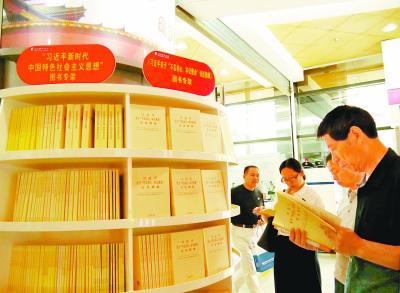 北京图书大厦设立的“习近平新时代中国特色社会主义思想”系列图书专架，深受读者喜爱。图为九月十一日，读者正在图书专架前认真阅读。本报记者 李丹阳摄/光明图片
