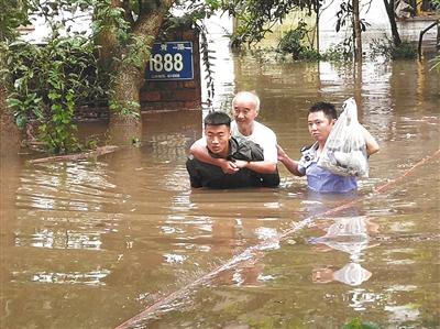 8月2日，四川乐山突降暴雨，河水漫过堤岸，民房被淹。当地民警和消防人员将被困老人背出。 乐山市公安局供图