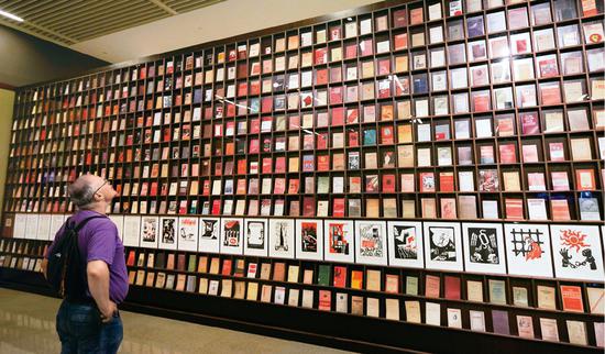 2018年5月9日，一位外国观众被北京“真理的力量——纪念马克思诞辰200周年主题展览”中一面展示不同国家出版的500多种《共产党宣言》的书墙所吸引。 中新社记者　贾天勇/摄