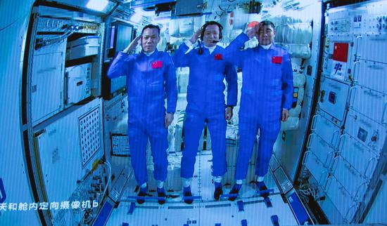 ↑6月17日在北京航天飞行控制中心拍摄的进驻天和核心舱的航天员向全国人民敬礼致意的画面。