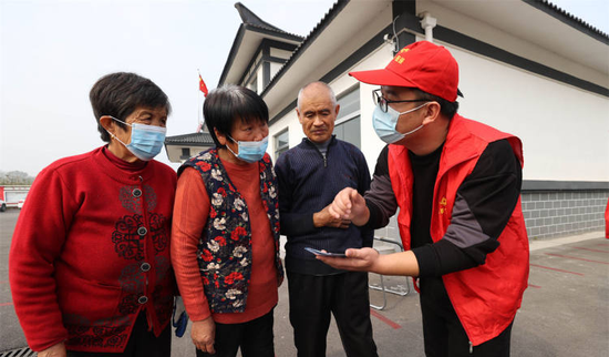 2021年11月4日，江苏省徐州市丰县医保局志愿者向村民讲解医保长期护理保险惠民政策（图 | 视觉中国）