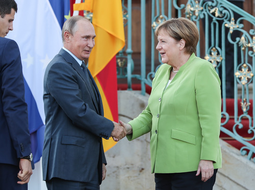 2018年8月18日，在德国首都柏林以北小镇梅泽贝格，德国总理默克尔（右）与来访的俄罗斯总统普京握手。新华社记者单宇琦摄