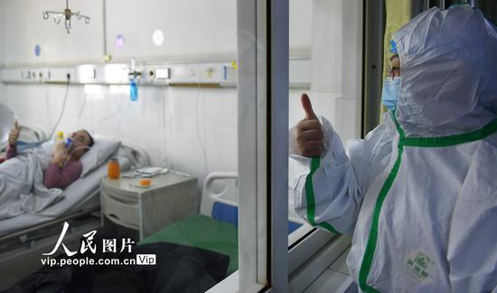 2020年1月29日，六安市人民医院感染科护士长李维玲（右一）和隔离病房内的患者相互相互鼓劲加油。陈力/人民图片