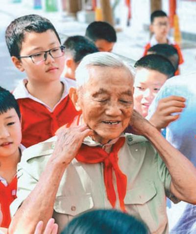 朱再保讲完课后,小学生给他系上红领巾.资料照片