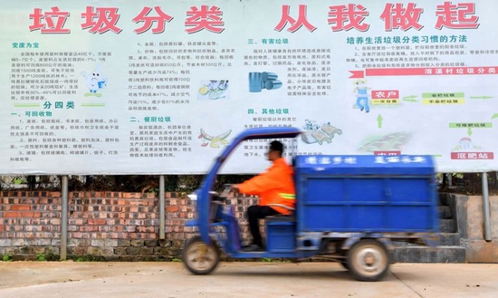  ↑在江西省永新县莲洲乡溶溪村，村里的保洁员从垃圾分类宣传栏前经过（2017年10月18日摄）。