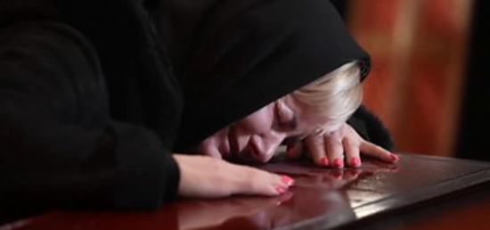 乌克兰女人伏在棺椁上痛哭。图源：BBC