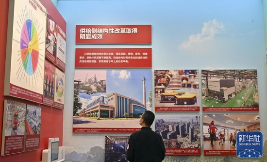 10月8日，一名观众在中央综合展区内观看供给侧结构性改革取得明显成效的展览内容。新华社记者 李鑫 摄