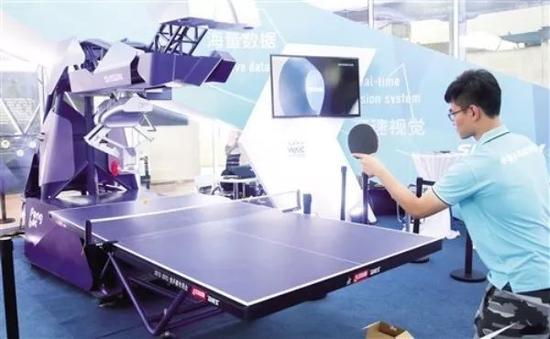  一名工作人员在2018世界人工智能大会现场演示与机器人打乒乓球。 （新华社发）