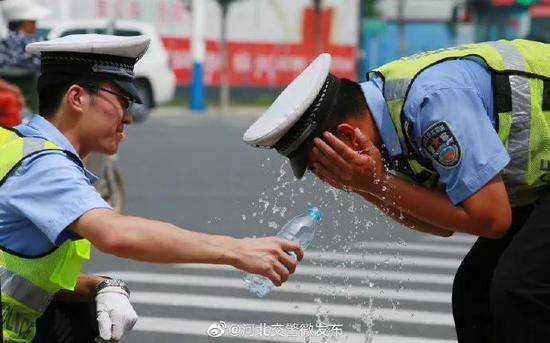 2019年5月22日，河北交警在高温下坚守岗位，用矿泉水降温。图片来源：河北省公安厅交通管理局官方微博。