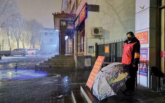 3月2日晚，雨雪天，北京慈善义工在社区门口值班。受访者供图