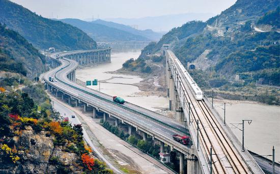 位于嘉陵江四川广元段的明月峡集“古栈道、古驿道、嘉陵江水道、纤夫道、公路、铁路”古今六道于一峡，集中展现了古代、近代、现代交通历史变迁的全过程。图为列车驶过广元嘉陵江特大桥。 中新社发 曹宁/摄