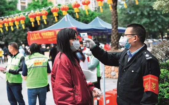 2月6日，广东省广州市白云区黄石街道白云尚城社区的工作人员对进入社区的人进行体温测量。摄影/新华社记者 卢汉欣