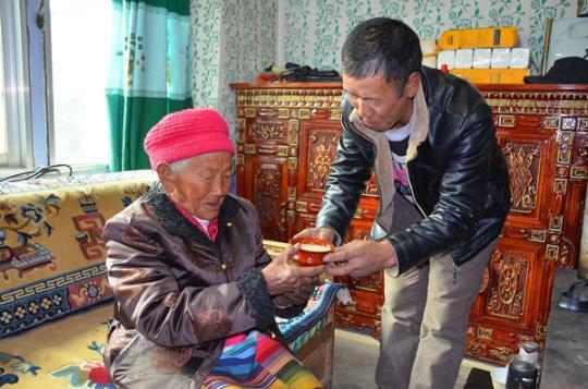 次仁卓嘎从儿子手中接过酥油茶。记者 刘枫 摄
