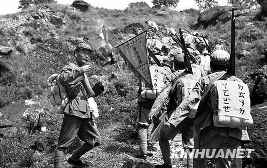 （图为1952年8月部队在行军中后面的战士通过前面一人后背的注音字母学识字 新华社记者岳国芳摄）