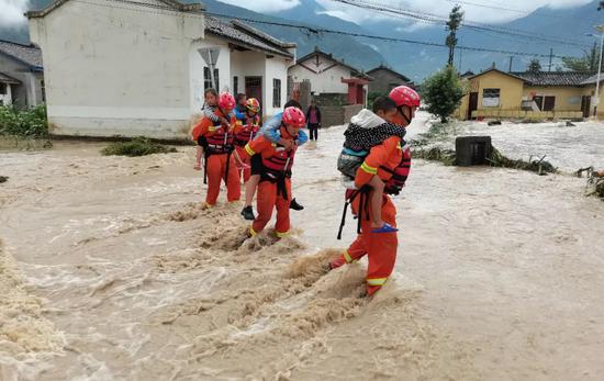 6月27日,四川省凉山彝族自治州冕宁县境内显现强降雨天气,消防声援人员在洪水中迁移儿童。