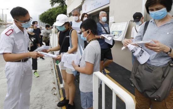 香港市民向门诊职员询问样本瓶使用及交还方法。图源：香港东网