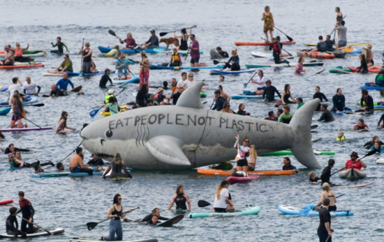 6月12日，民众在海上乘坐皮划艇，聚集在“充气鲨鱼”道具附近抗议。