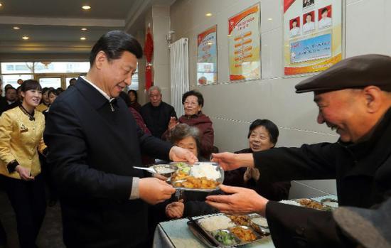 2013年2月4日，在兰州一家“虚拟养老院”的养老餐厅，习近平端上一盘热气腾腾的饭菜送给就餐的老人（图片来源：新华网）