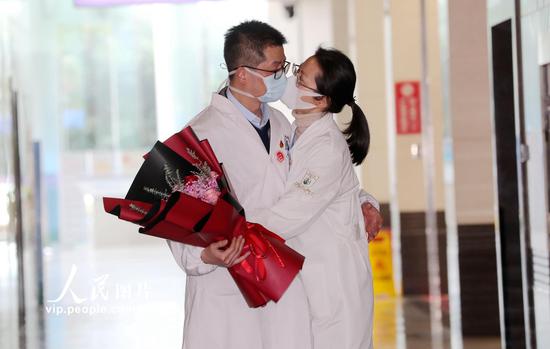 2020年2月9日，德清县人民医院主治医师吴峥明（左）与同为医护人员的妻子张奕“吻别”。谢尚国/人民图片