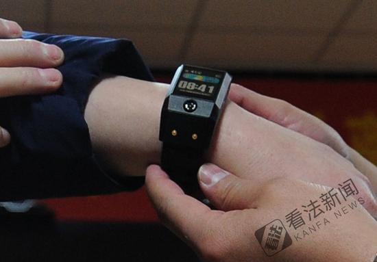 图为监狱民警为离监探亲的服刑人员佩戴电子手环 .摄/记者 林晖