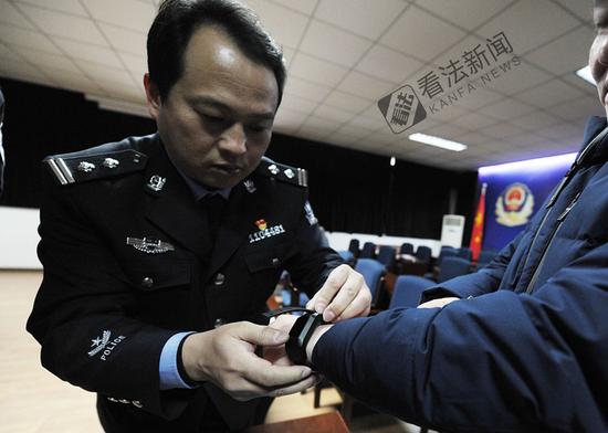 图为监狱民警为离监探亲的服刑人员佩戴电子手环 .摄/记者 林晖
