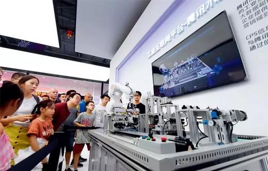 在位于重庆的2018 中国国际智能产业博览会现场，腾讯展区“木星云”工业互联网平台上一台机械手臂在进行加工作业 唐奕 摄