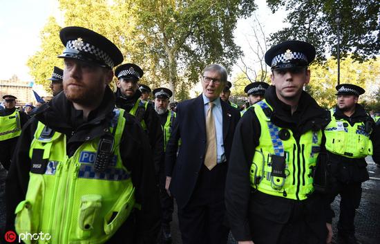 10月19日，英国伦敦，议员比尔·卡什在警方护送下离开议会大厦。图自IC Photo