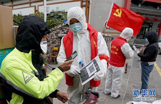 4月11日，疫情防控工作人员在武汉中华路街居民小区封控卡点，让出小区的人员扫描健康码。新华社记者 王毓国 摄